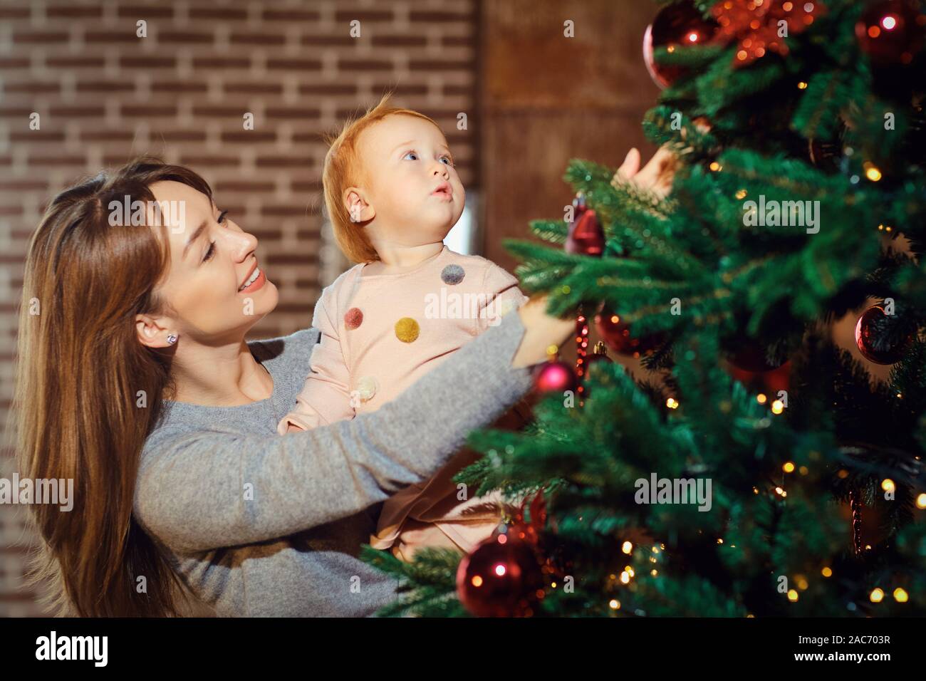 Smiling mother showing Christmas tree to baby Stock Photo