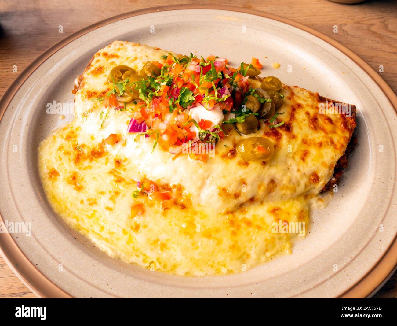 Vegetarian Enchilada Puy lentils in tortilla with melted cheese sour cream salsa and jalapeños Stock Photo