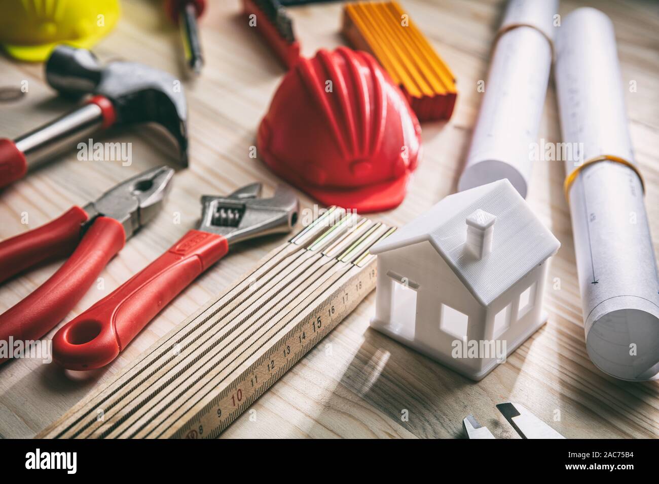 Construction, house renovation concept. Hand tools, hard hats and project blueprints on wood, close up view Stock Photo