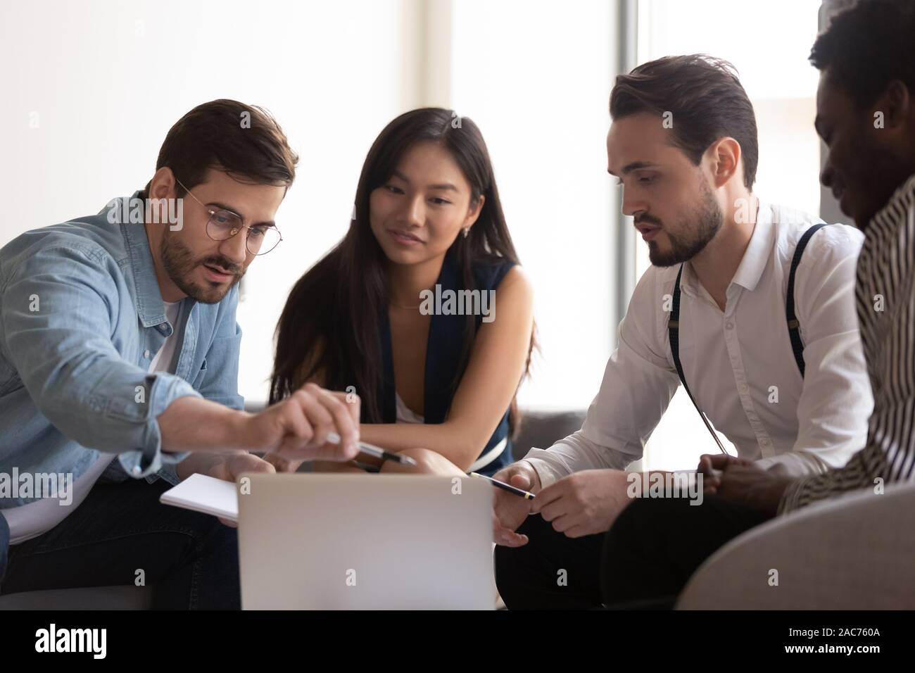 Team leader explain to diverse colleagues corporate program using notebook Stock Photo