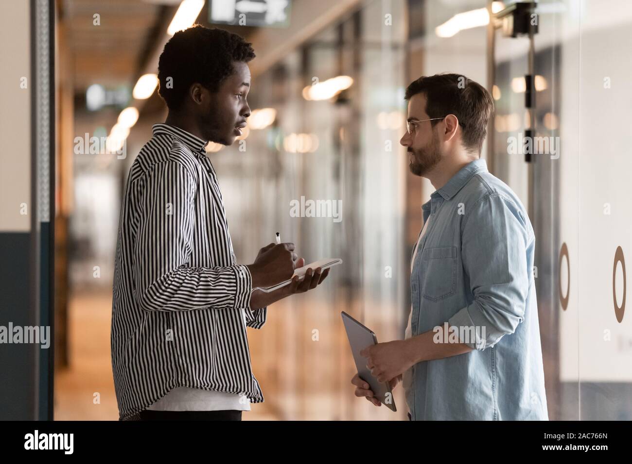 Multi-ethnic colleagues standing in office hallway and talking Stock Photo