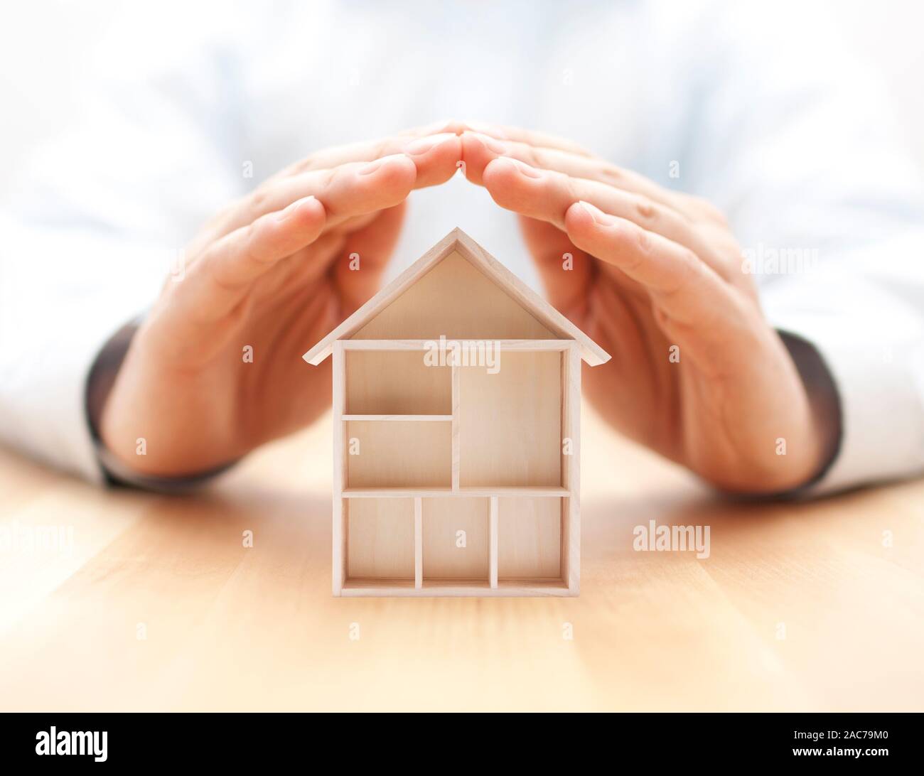 Wooden house protected by hands Stock Photo