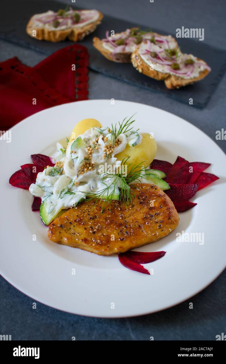 Food photography of a vegan cutlet, boiled potatoes and a dill and yogurt sauce on a black schist background and a red cloth Stock Photo