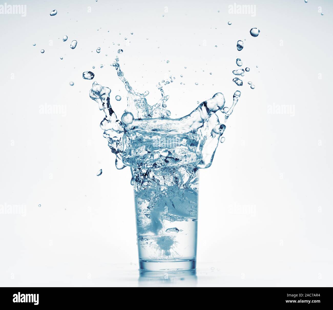 one glass of water with splash from falling ice cube, white background ...