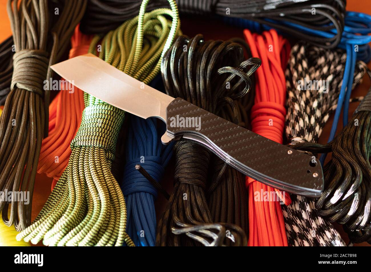 Pocket knife and multicolored ropes. Folding knife and paracord. Multi