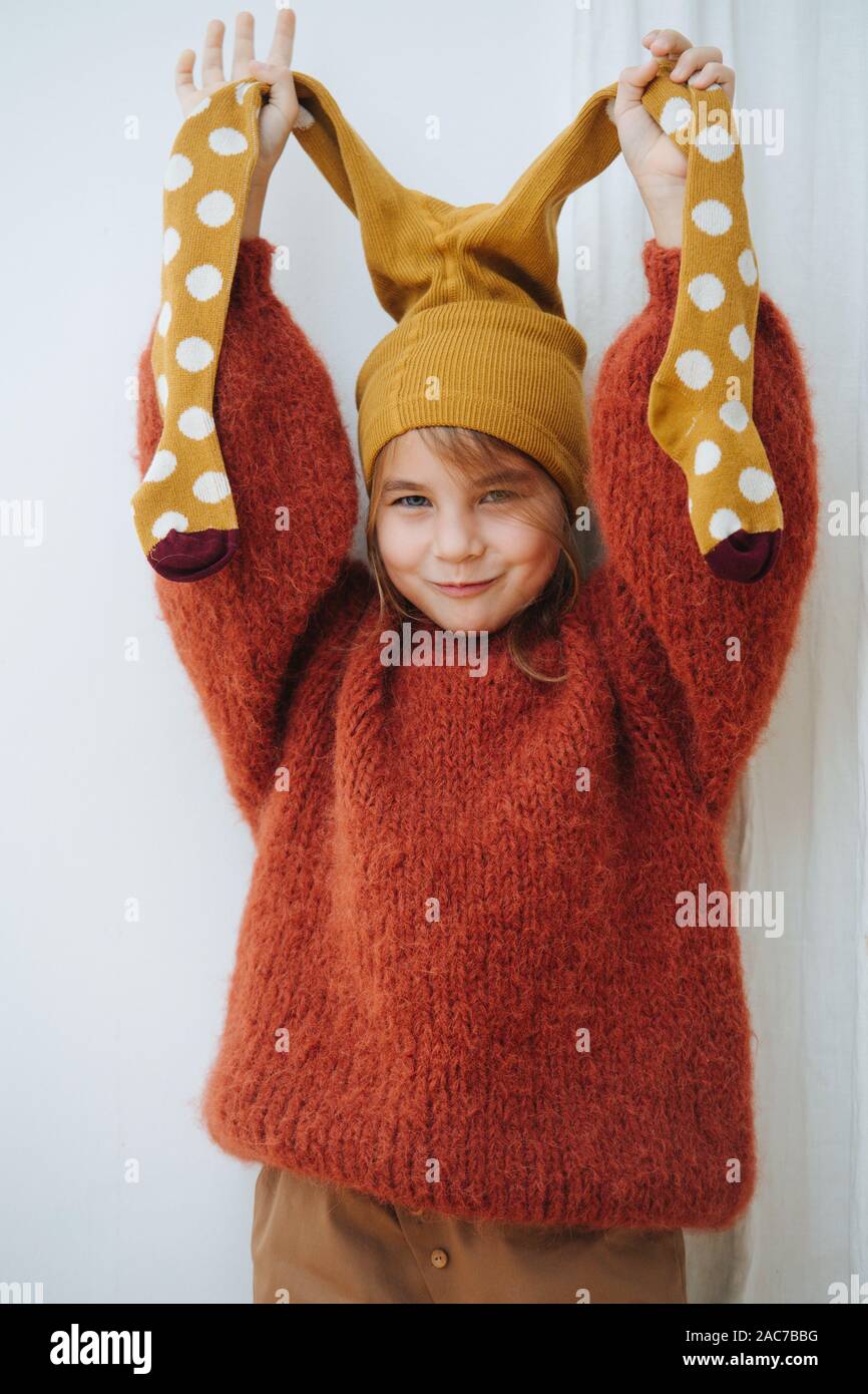 Little girl in dark orange knitted sweater with tights on her head Stock Photo Alamy