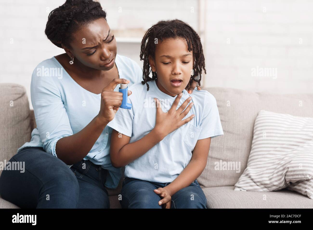Black mother holding asthma inhaler for daughter Stock Photo