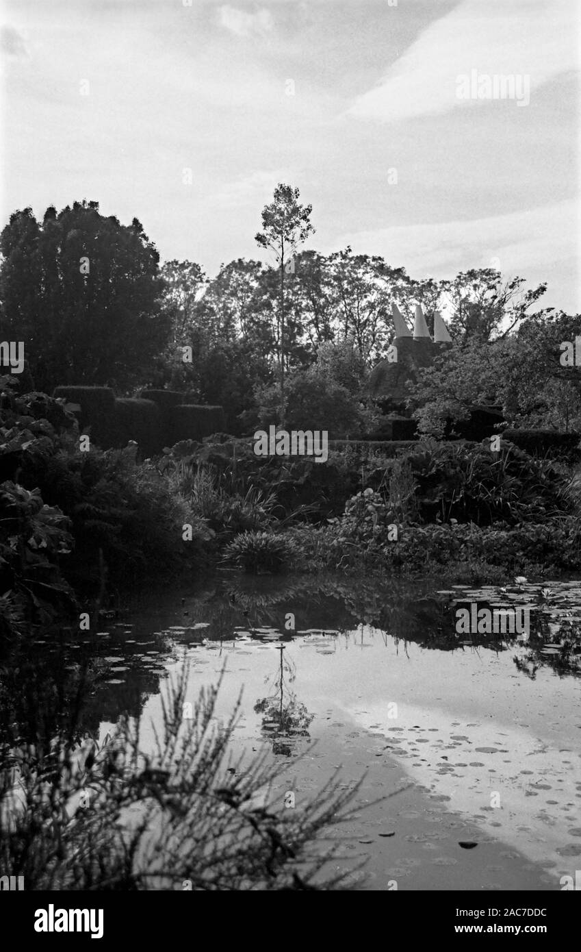 Great Dixter: lake and oast houses.  Garden by Christopher Lloyd and Edwin Lutyens.  Old black and white film photograph, circa 1980 Stock Photo