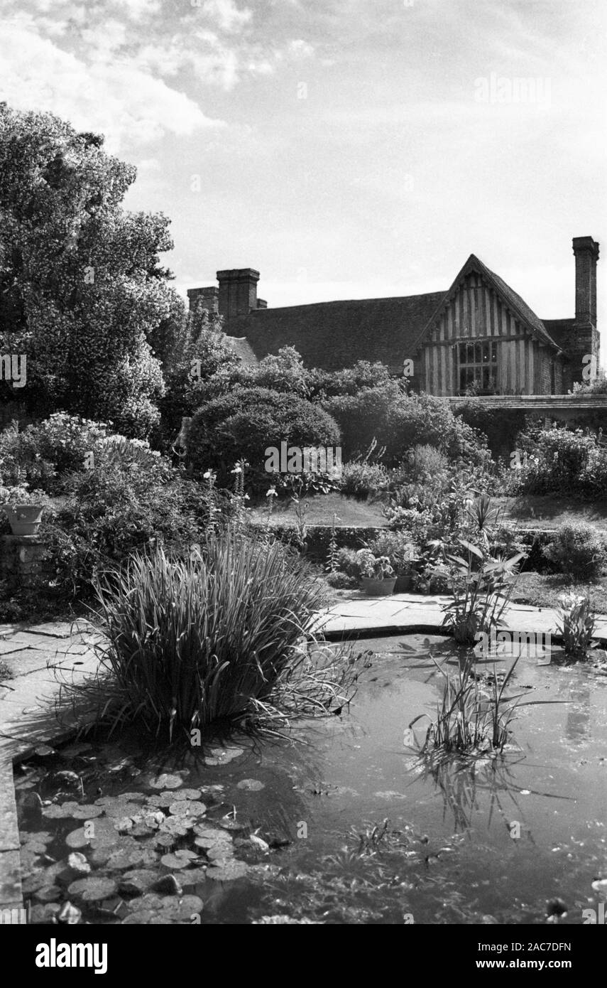 Gabled front of Great Dixter Manor, built circa 1450, seen across part of Christopher Lloyd's Sunken Garden.  Old black and white film photograph, circa 1980 Stock Photo