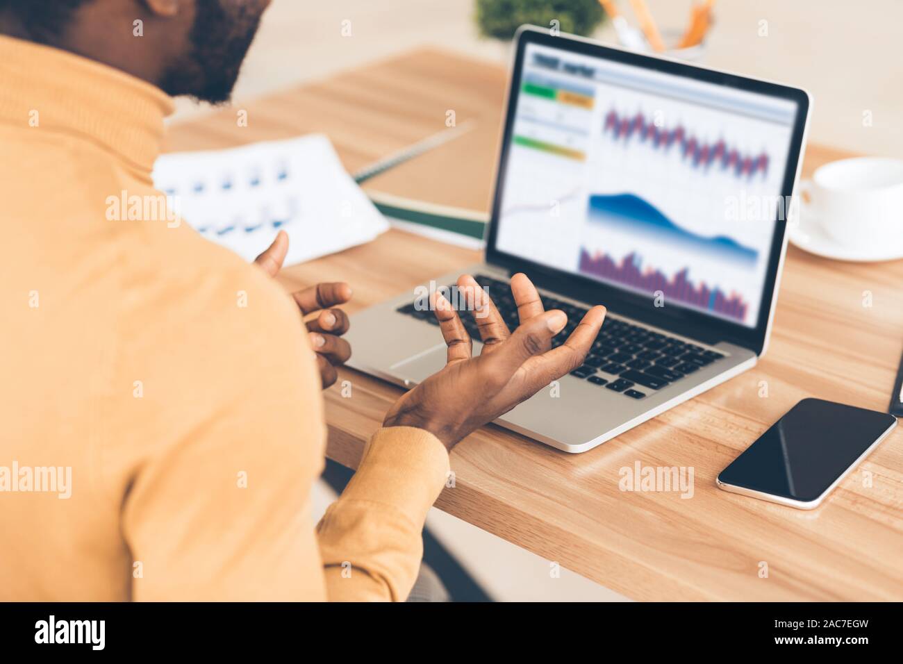 Stressed afro businessman looking at graphs on screen Stock Photo