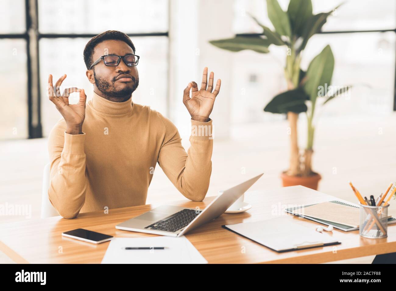 Black man meditating in office coping with stress Stock Photo