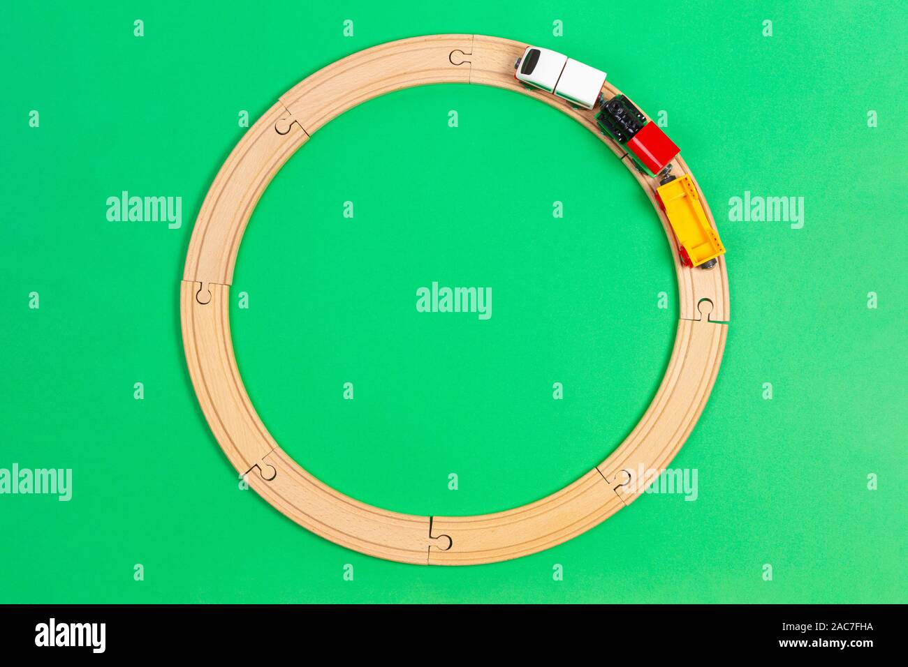 Toy train moves on round wooden railways on light green background. Top