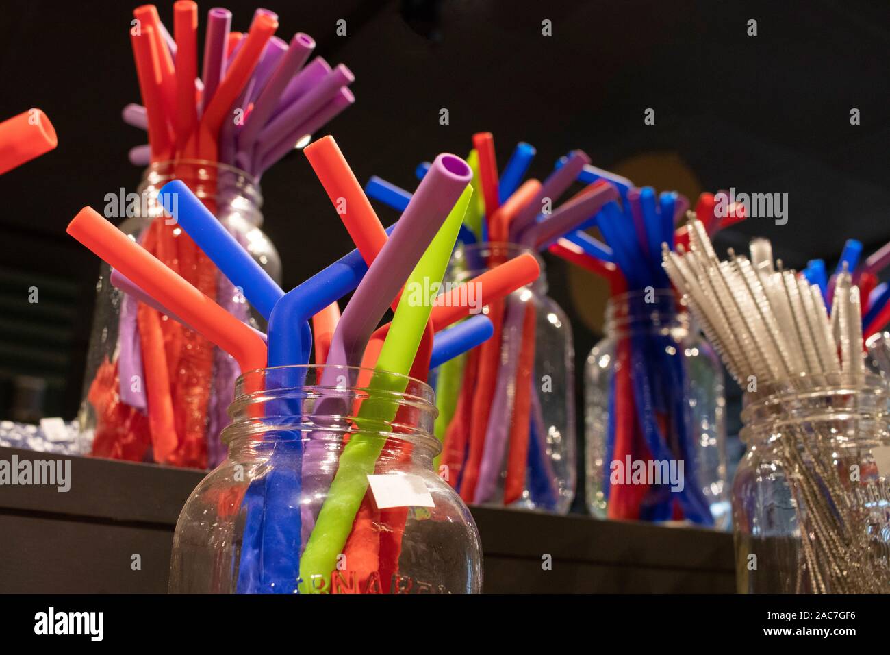 Multicolor silicone reusable straws and clearning brushes display in Mason Jars, zero waste shop, sustainable pratices Stock Photo