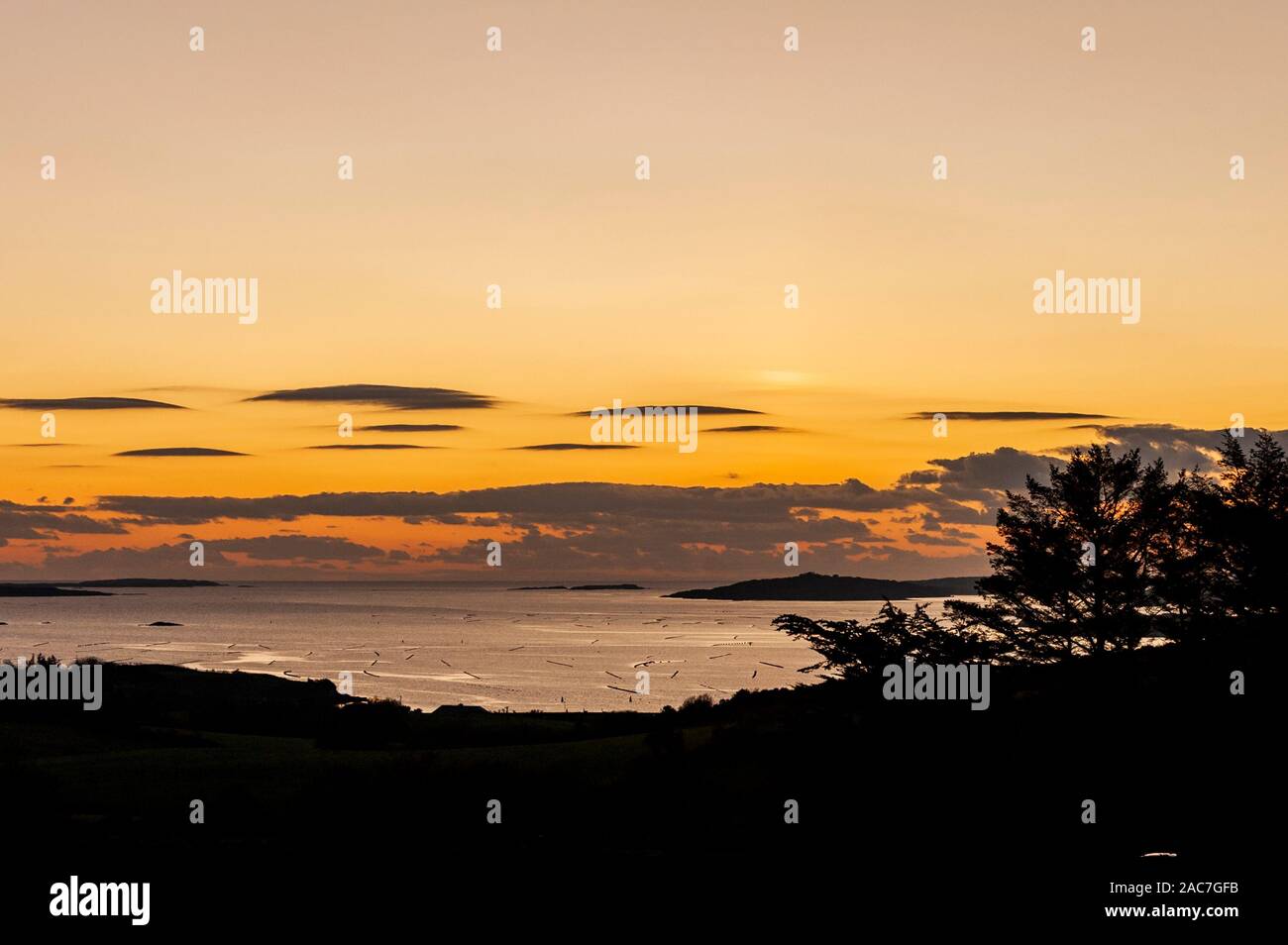 Roaring Water Bay, West Cork, Ireland. 1st Dec, 2019. The sun sets over the mussel farms in Roaring Water Bay leaving a stunning orange hue after a day of sunshine. Credit: Andy Gibson/Alamy Live News Stock Photo