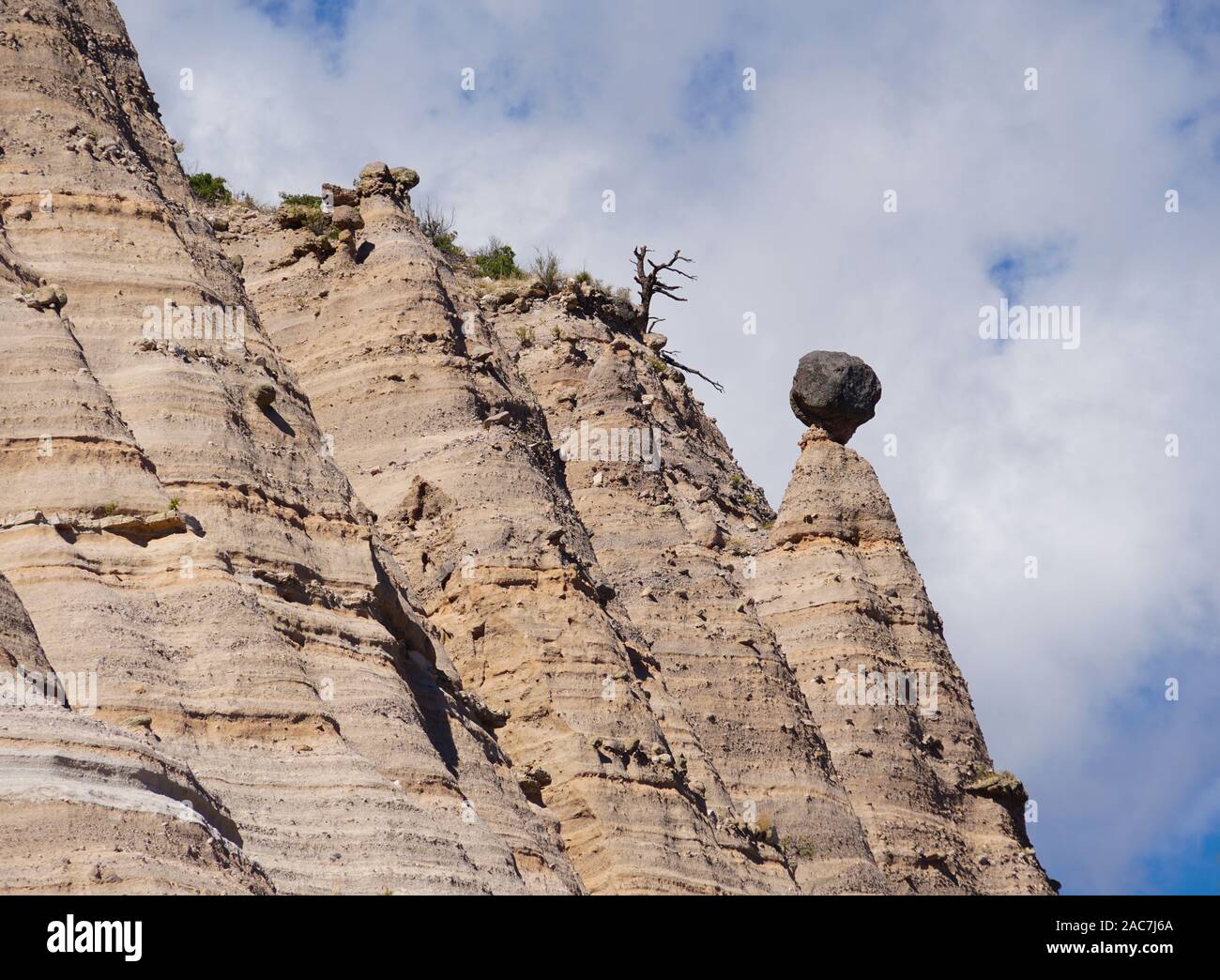 A large boulder balances precariously on top of a sandstone tapered column in the Kasha-Katuwe Tent Rocks National Monument. Stock Photo
