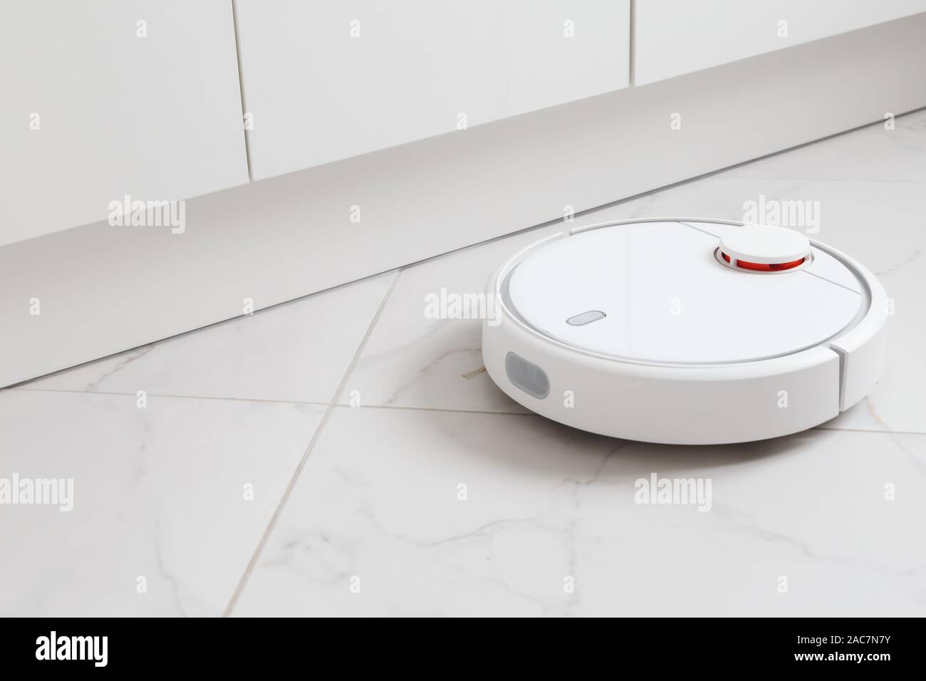 Robot vacuum cleaner vacuuming tiles in room Stock Photo Alamy