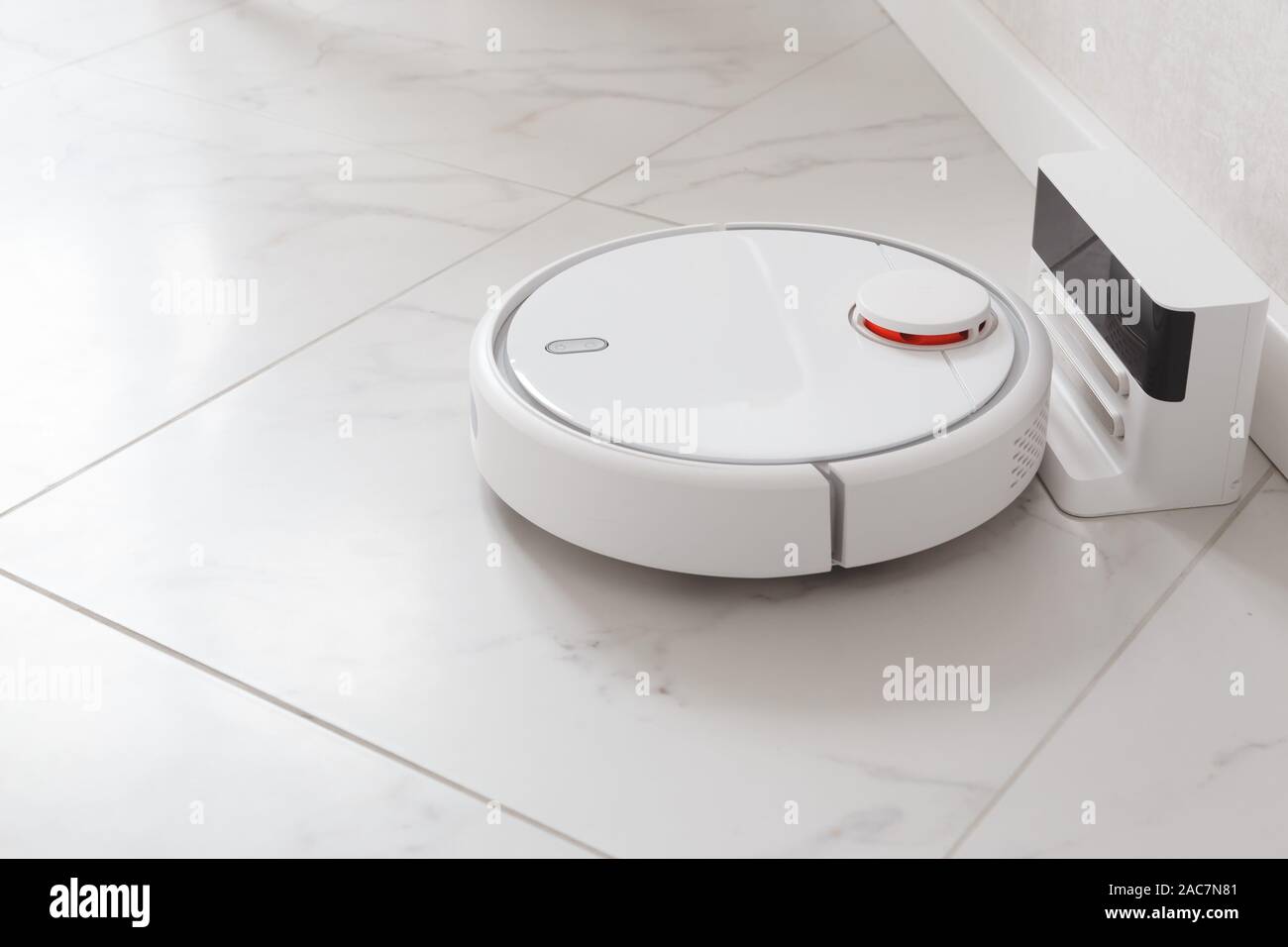 Robot vacuum cleaner on charging. Room with white ceramic tile and