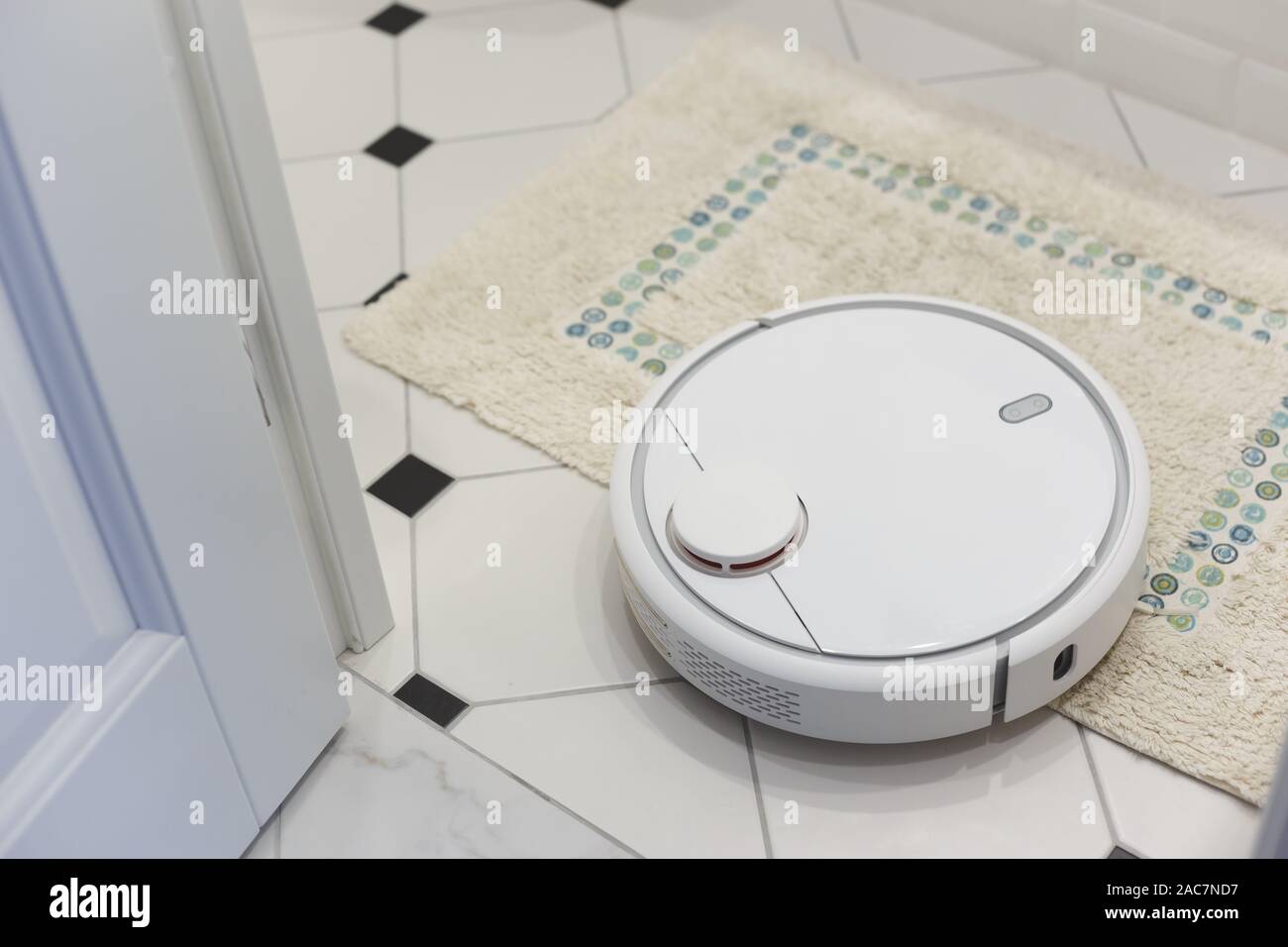 White robot vacuum cleaner on carpet in bathroom Stock Photo - Alamy