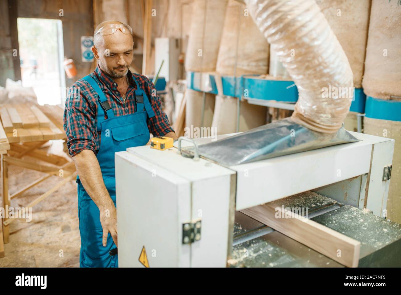 Carpenter works on plane machine, woodworking Stock Photo
