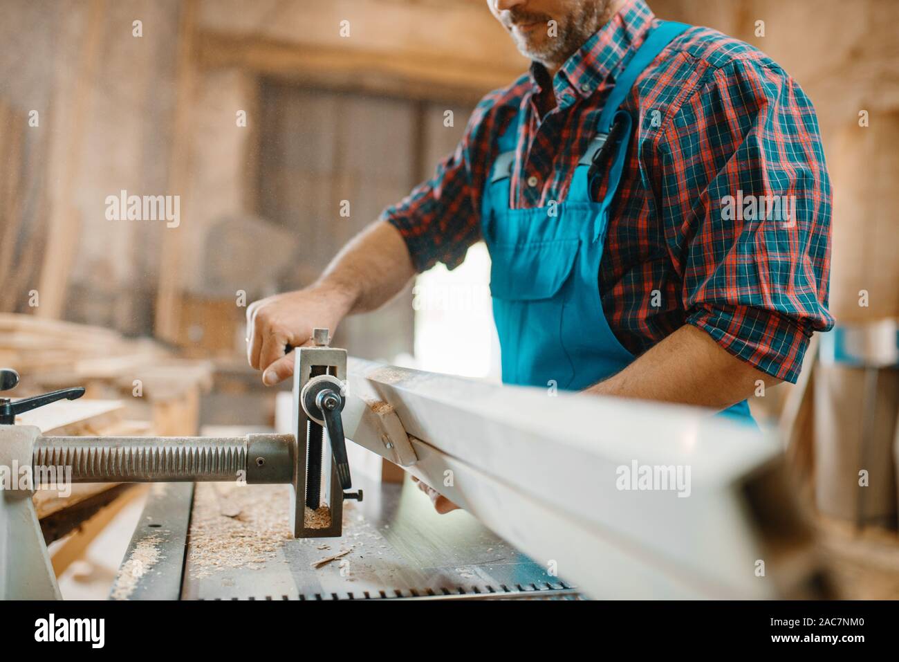 Carpenter works on plane machine, woodworking Stock Photo