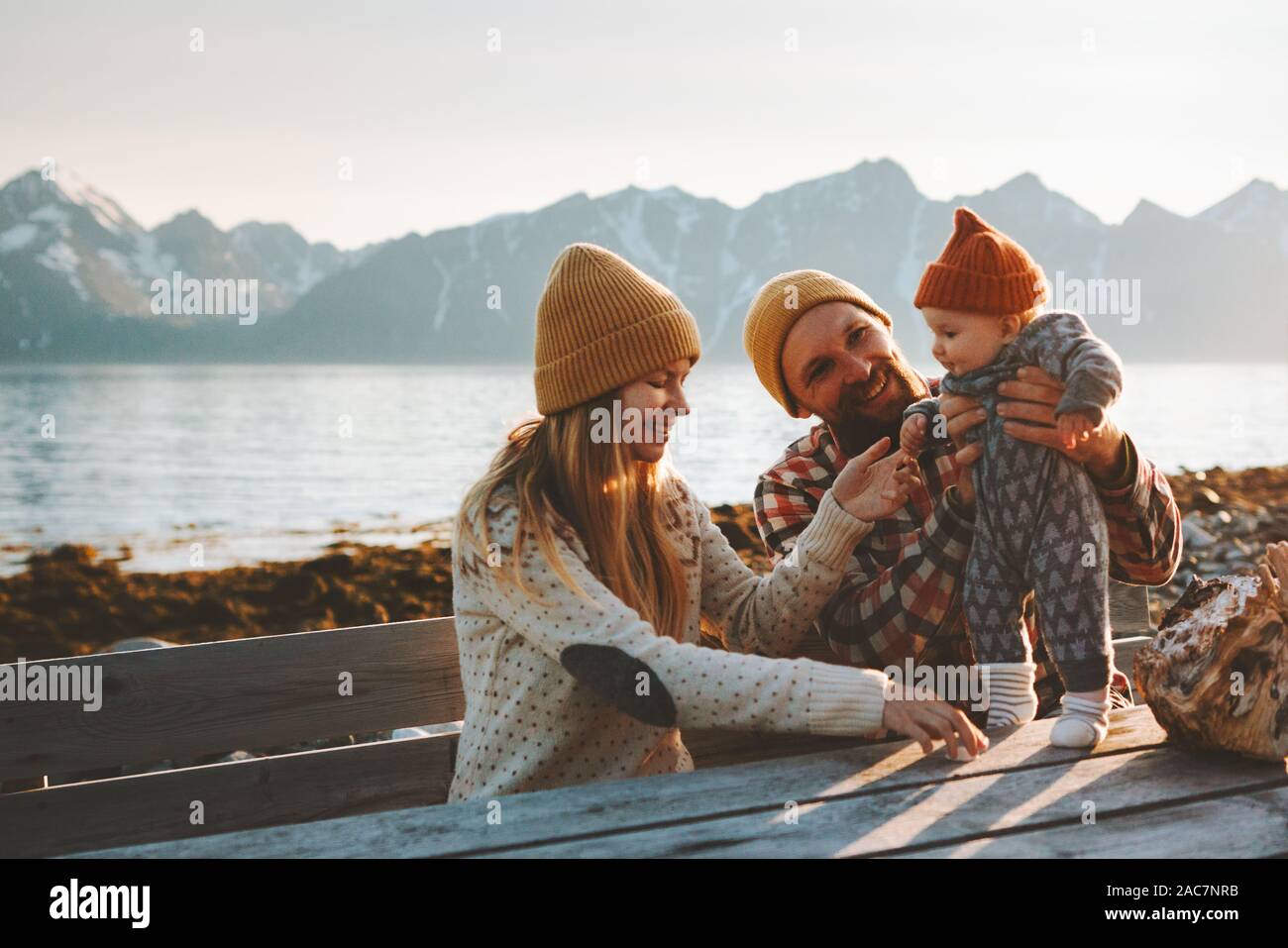 Happy family outdoor mother and father with baby traveling together vacation parents playing with child healthy lifestyle mountains view in Norway Stock Photo