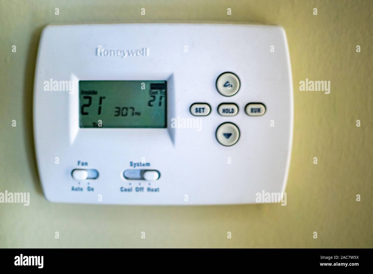 A honeywell thermostat for home central heating fixed to a wall Stock Photo