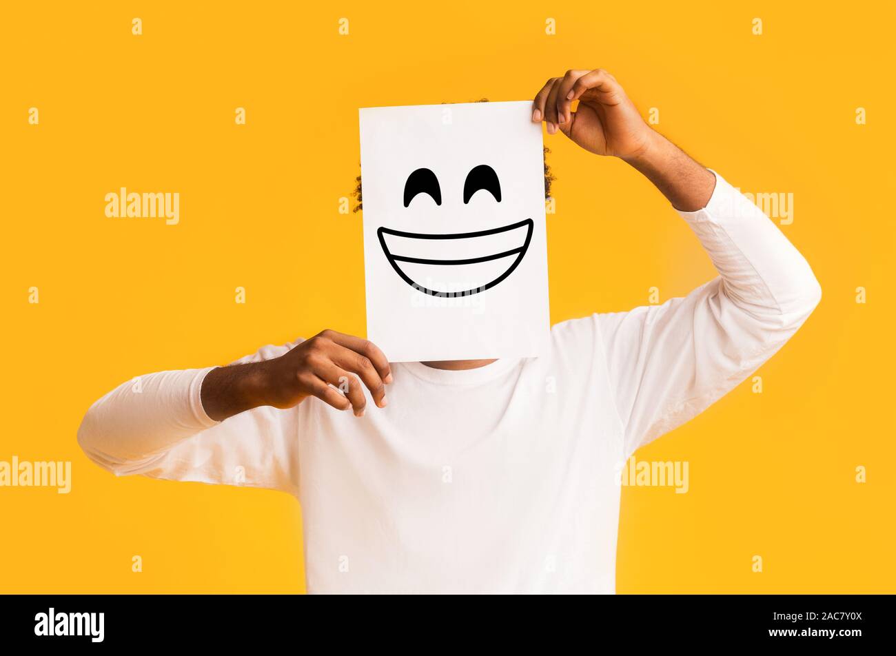 African american man holding paper with smiley face Stock Photo