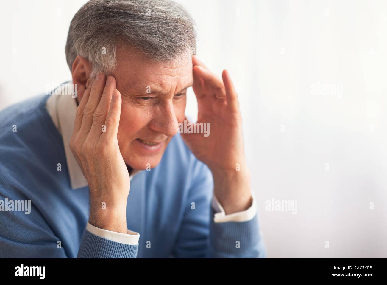 Elderly Gentleman Having Headache Massaging Temples Sitting Indoor