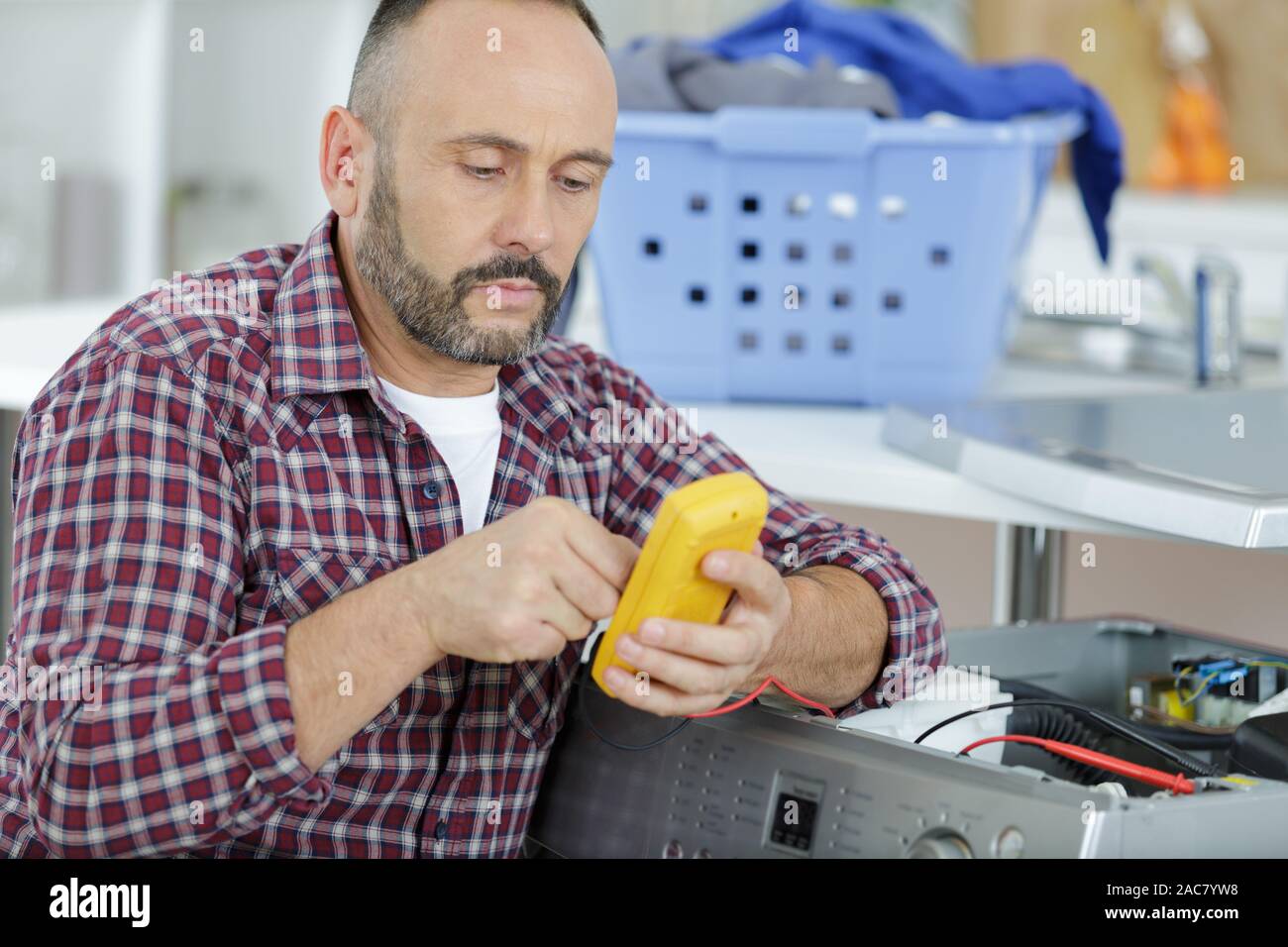 man using a multimeter to find washing machine fault Stock Photo