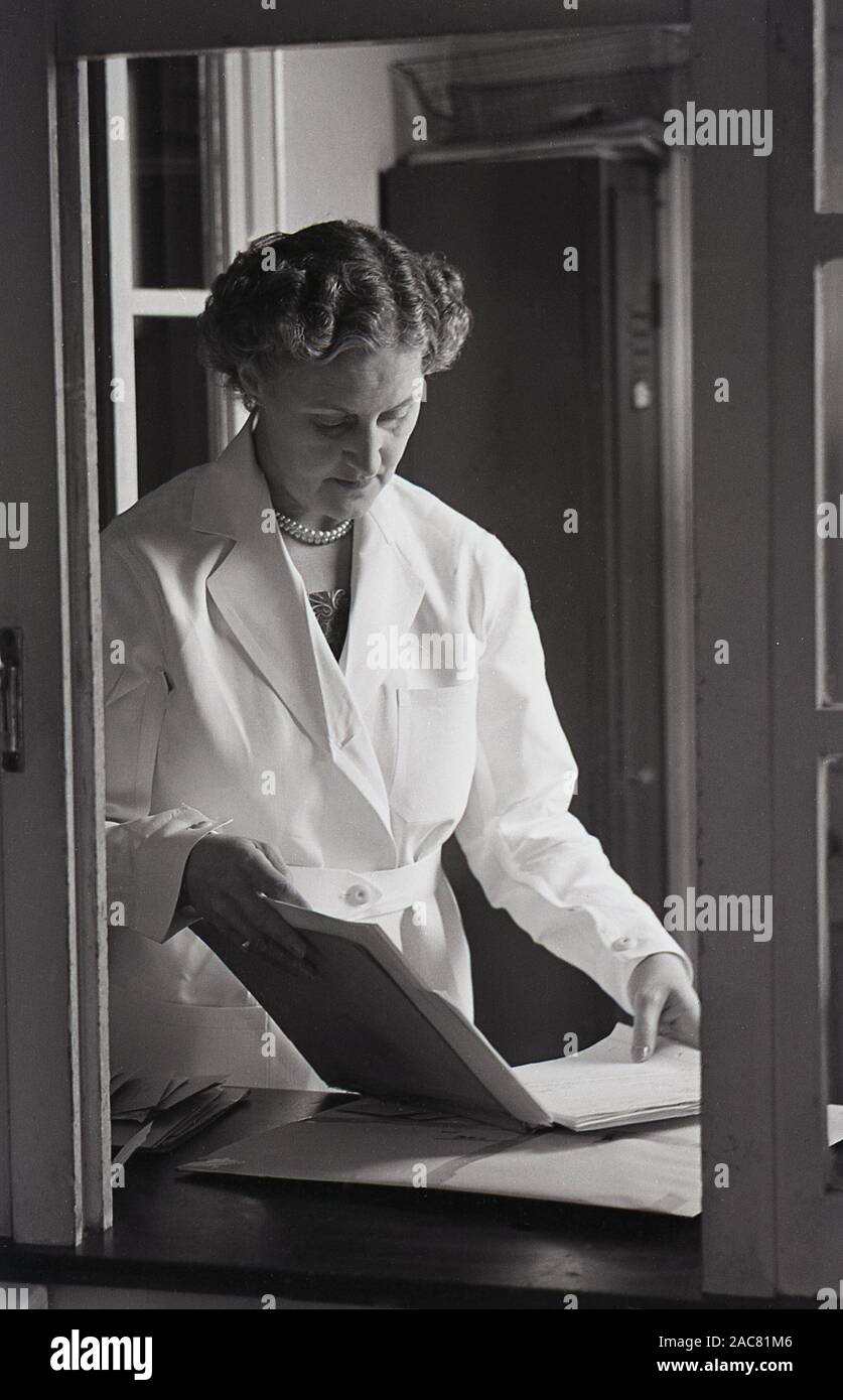 1950s, historical, a hospital matron standing in her office looking at a patient's medical notes, England, UK. Stock Photo