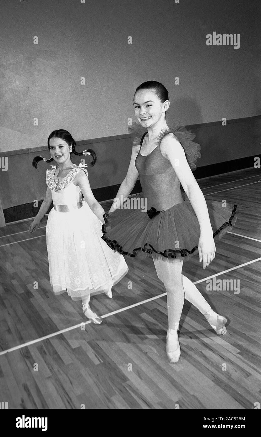 1980s, historical, two young girls dancing inside a school hall, both in ballet costumes, one wearing a tutu with camisole leotard, England, UK. Stock Photo