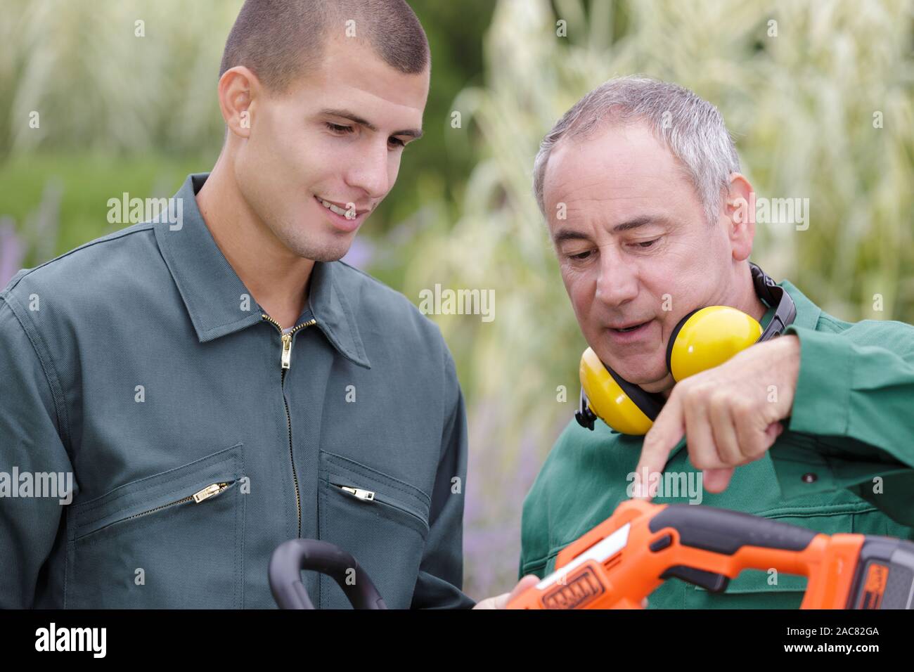 young male gardener learning how to use machine Stock Photo