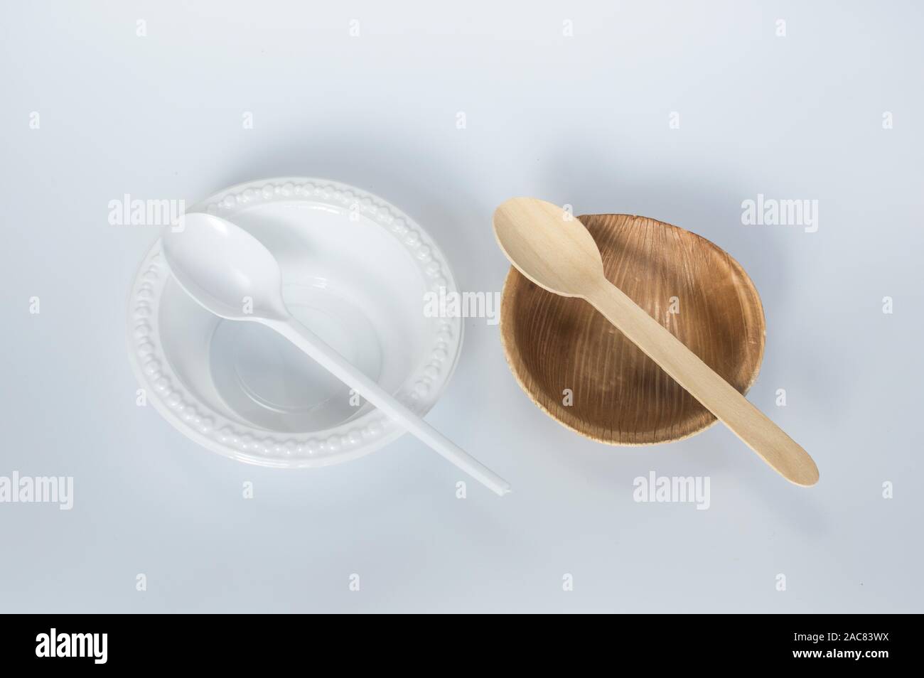 Top down view of a side by side comparison of a single use plastic cup and spoon against a palm leaf based cup and wooden spoon Stock Photo