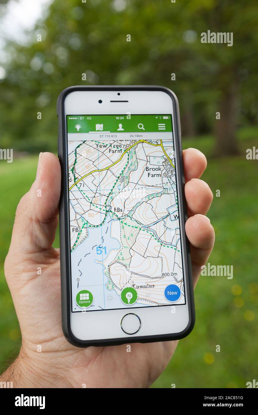 BATH, UK - SEPTEMBER 1, 2015 : Close-up of a male hand holding up a smartphone displaying an Ordnance Survey map in the ViewRanger application. Stock Photo