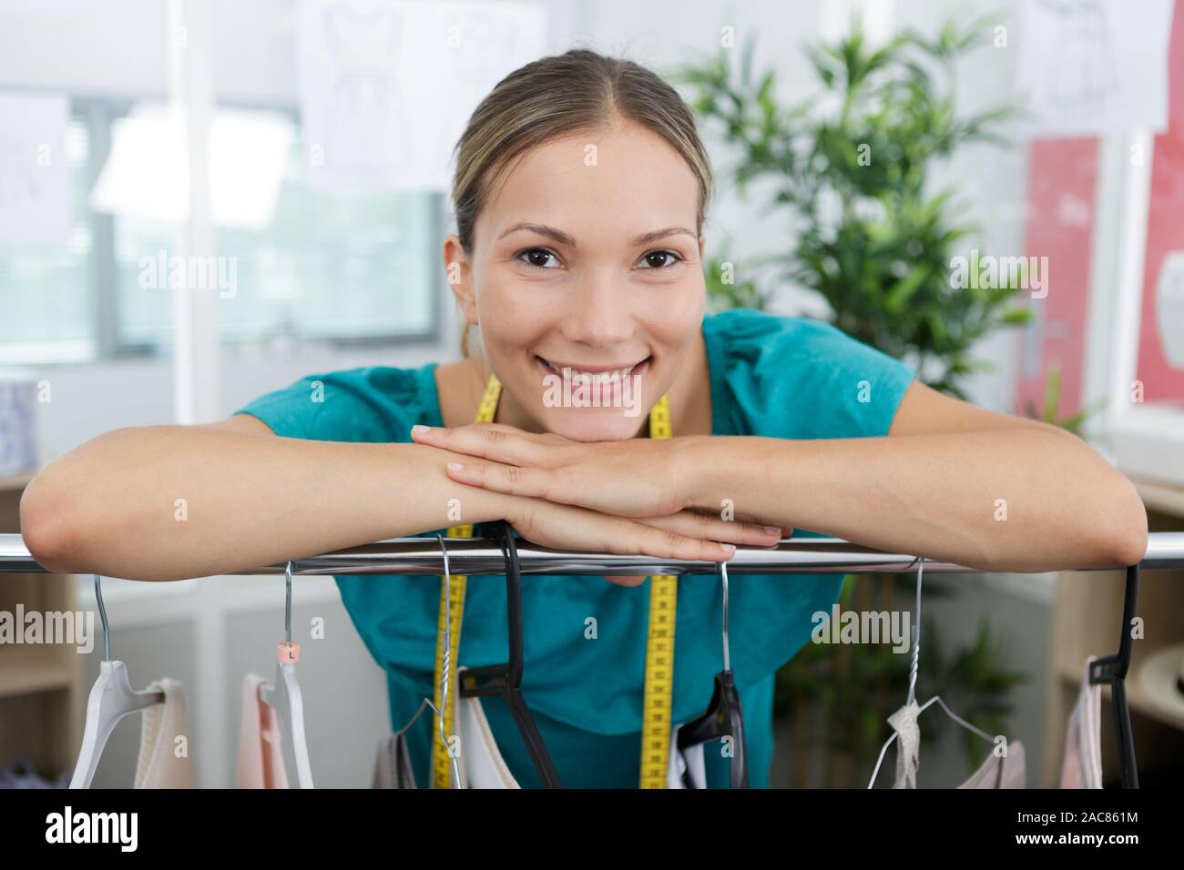 seamstress posing leaning on clothing rack Stock Photo Alamy