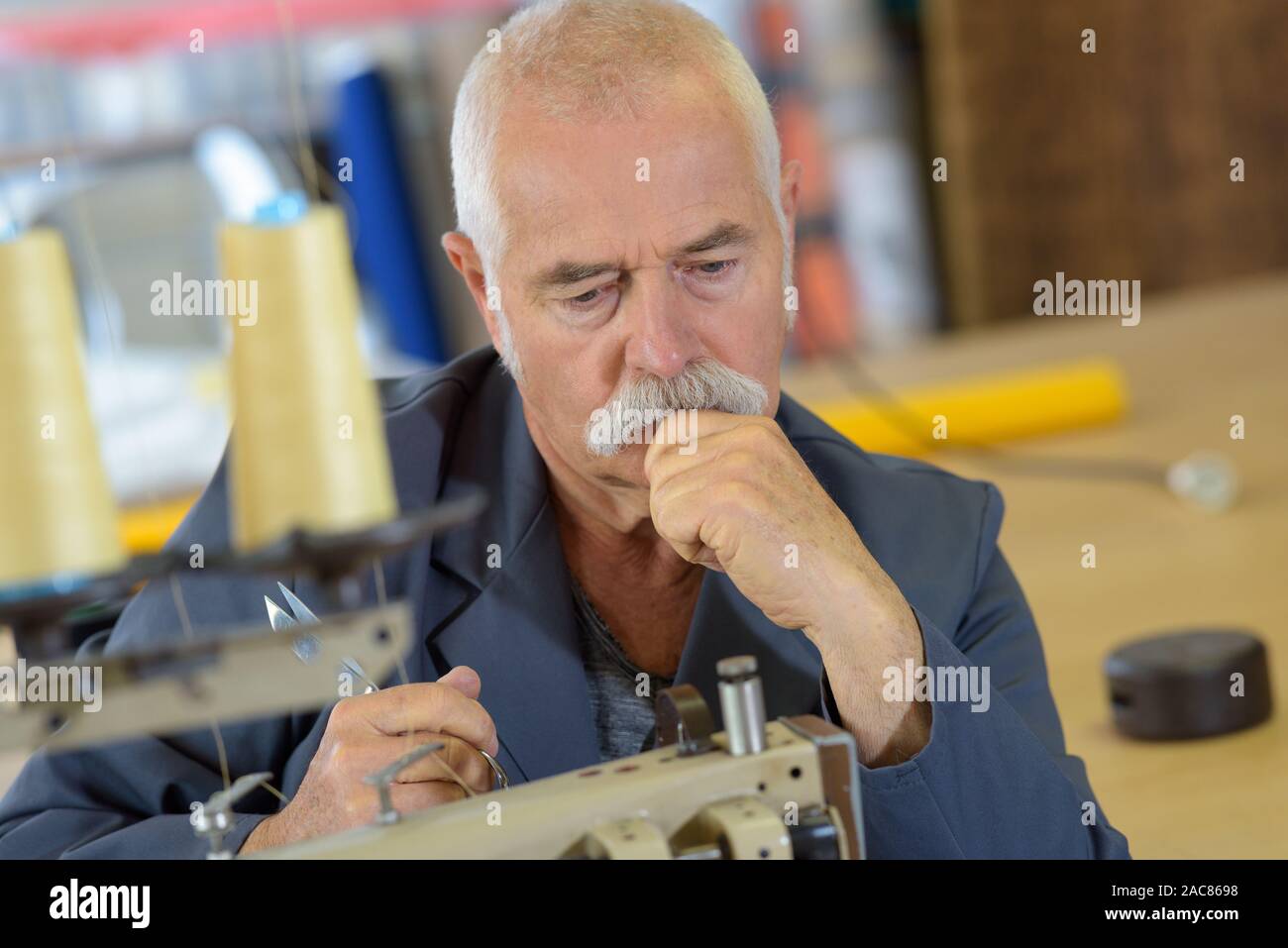 pensive senior man using industrial sewing machine Stock Photo