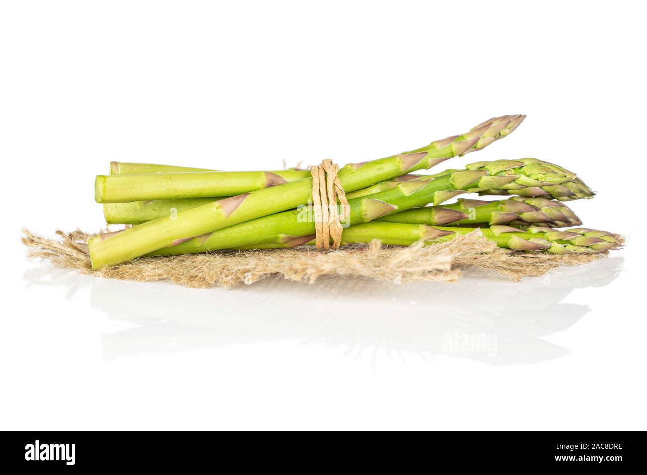 Lot of whole healthy green asparagus with straw rope and jute fabric isolated on white background Stock Photo