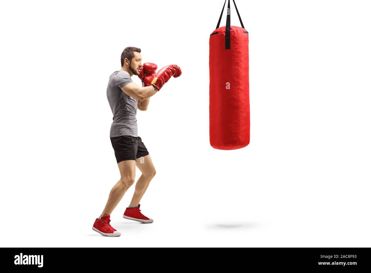 Full length shot of a young athlete training box with a punching bag isolated on white background Stock Photo