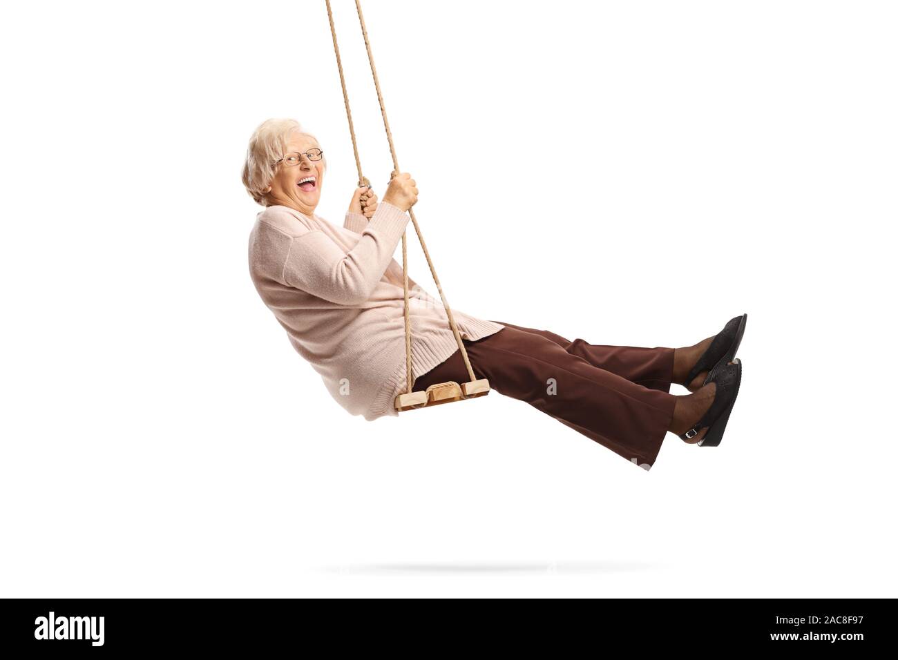Senior lady swinging on a swing and laughing isolated on white background Stock Photo