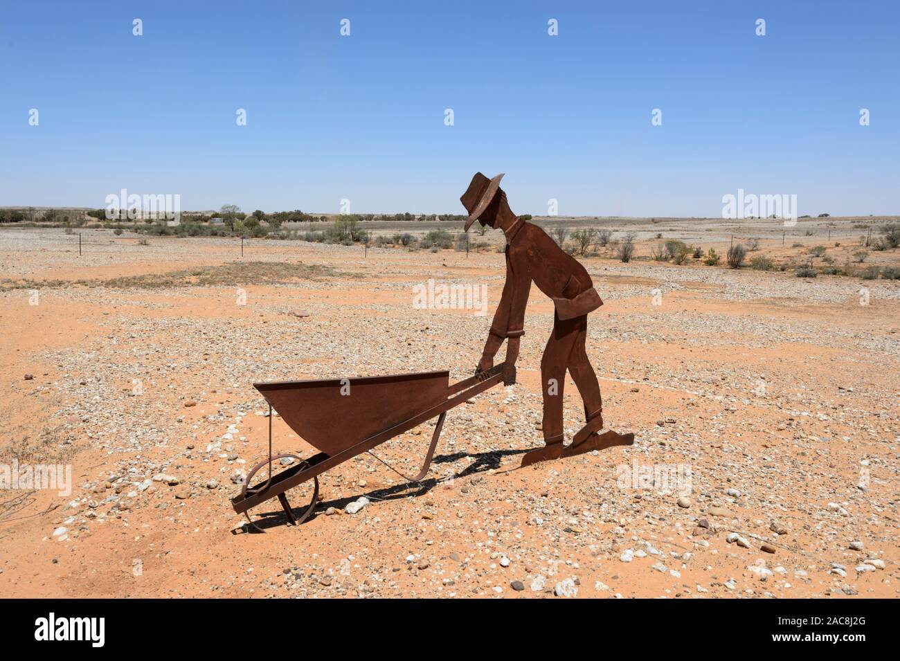 Metal statue of a gold miner pushing a wheelbarrow in the historic remote Outback town of Milparinka, New South Wales, NSW, Australia Stock Photo