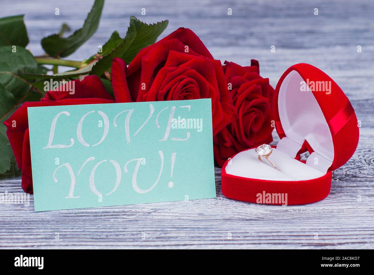 Golden Ring And Card With Inscription Love You Red Roses With