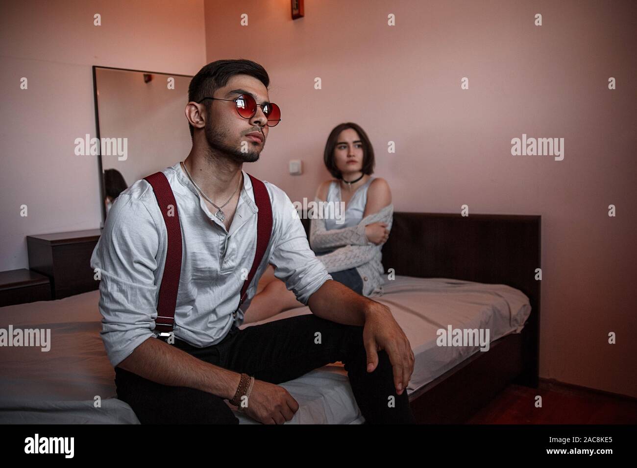 A Young Stylish Guy In Glasses Sits On The Edge Of The Bed With A Thoughtful Sad Face Behind Him Lies A Young Brunette Girl Stock Photo Alamy A Young Stylish Guy In Glasses Sits On The Edge Of The Bed With A Thoughtful Sad Face Behind Him Lies A Young Brunette Girl Stock Photo Alamy