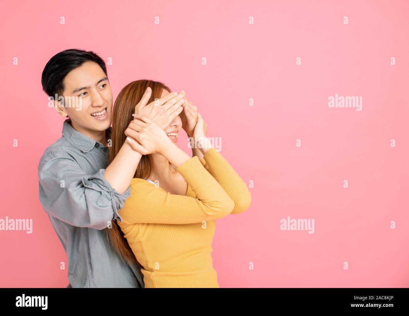 young man covering girl's eyes to surprise her Stock Photo