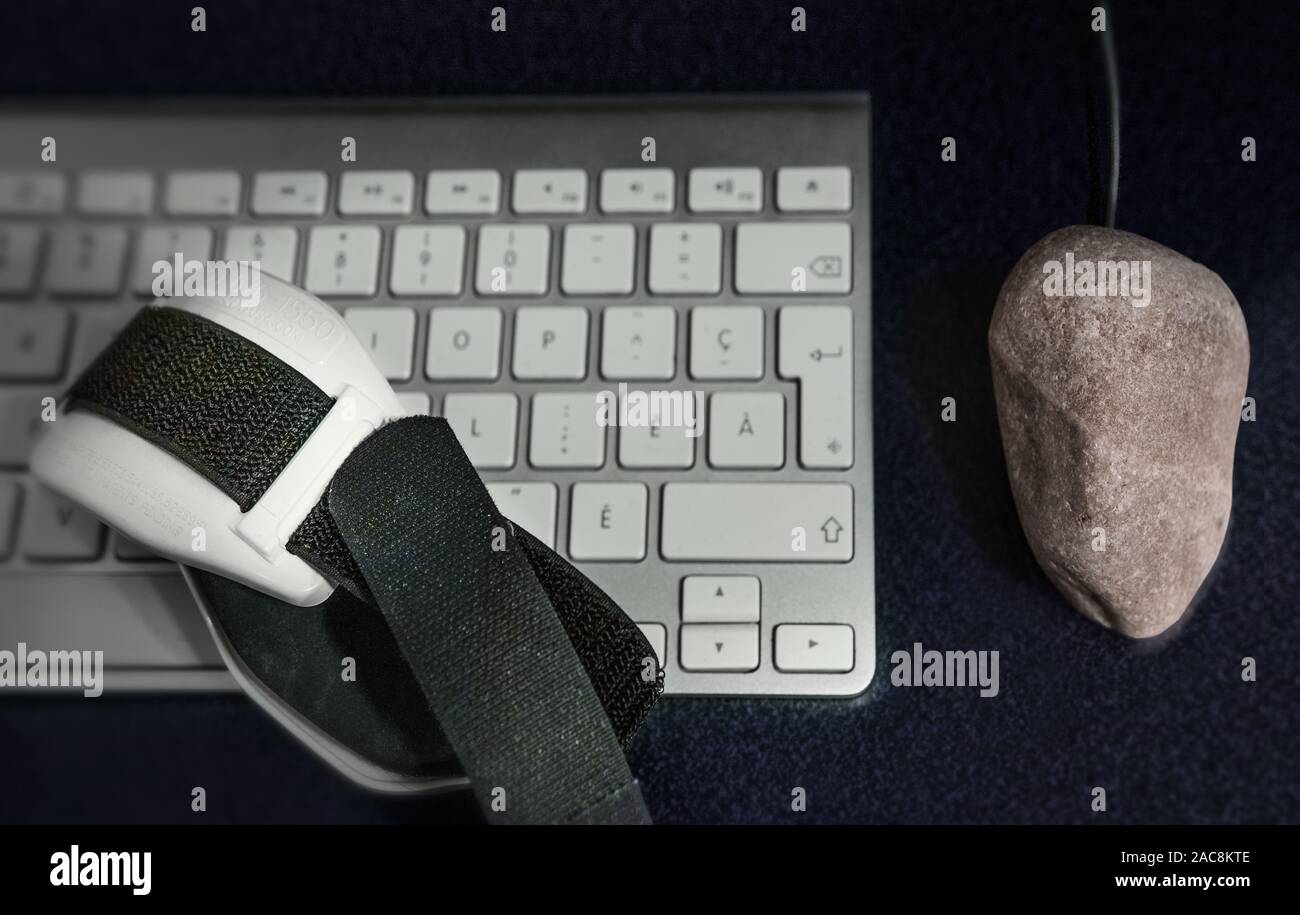 instead of the mouse of the computer we have a rock..which symbolizes the inadequate equipment that affects the long-term health of the person. Stock Photo