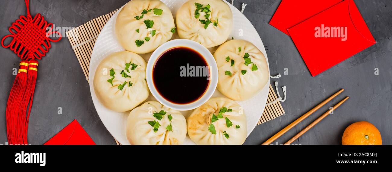Chinese New Year decoration with dumplings, tangerines, soy sauce, chopsticks, red envelopes on gray concrete background. Happy Chinese new year 2020 Stock Photo