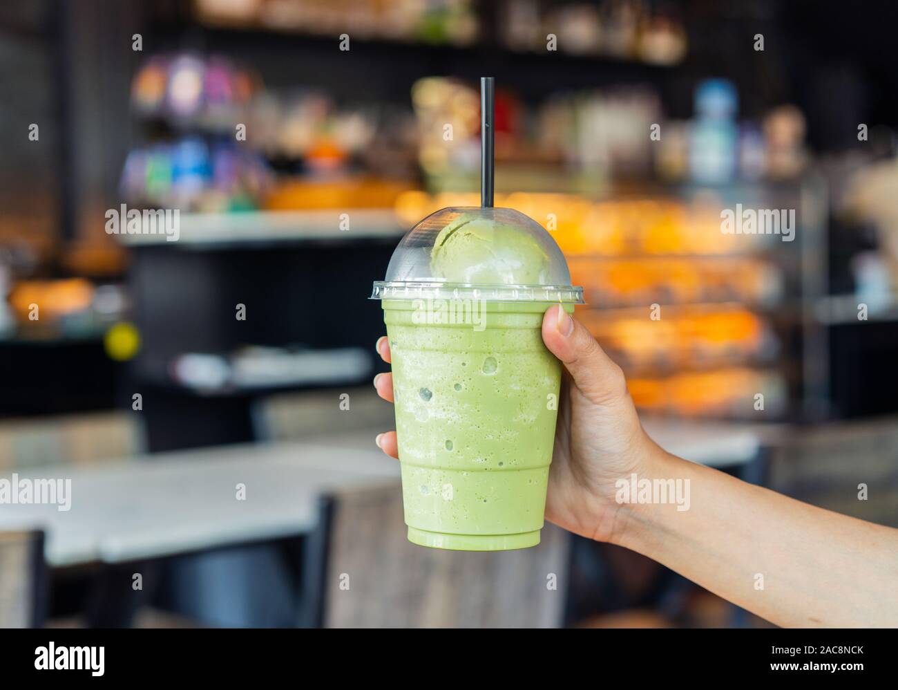 hand holding glass of Green tea frappe with ice cream in cafe Stock