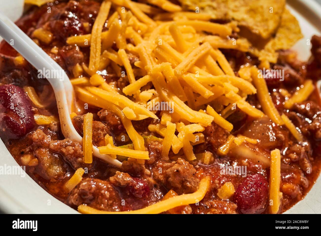 A bowl of chili with shredded yellow cheese Stock Photo