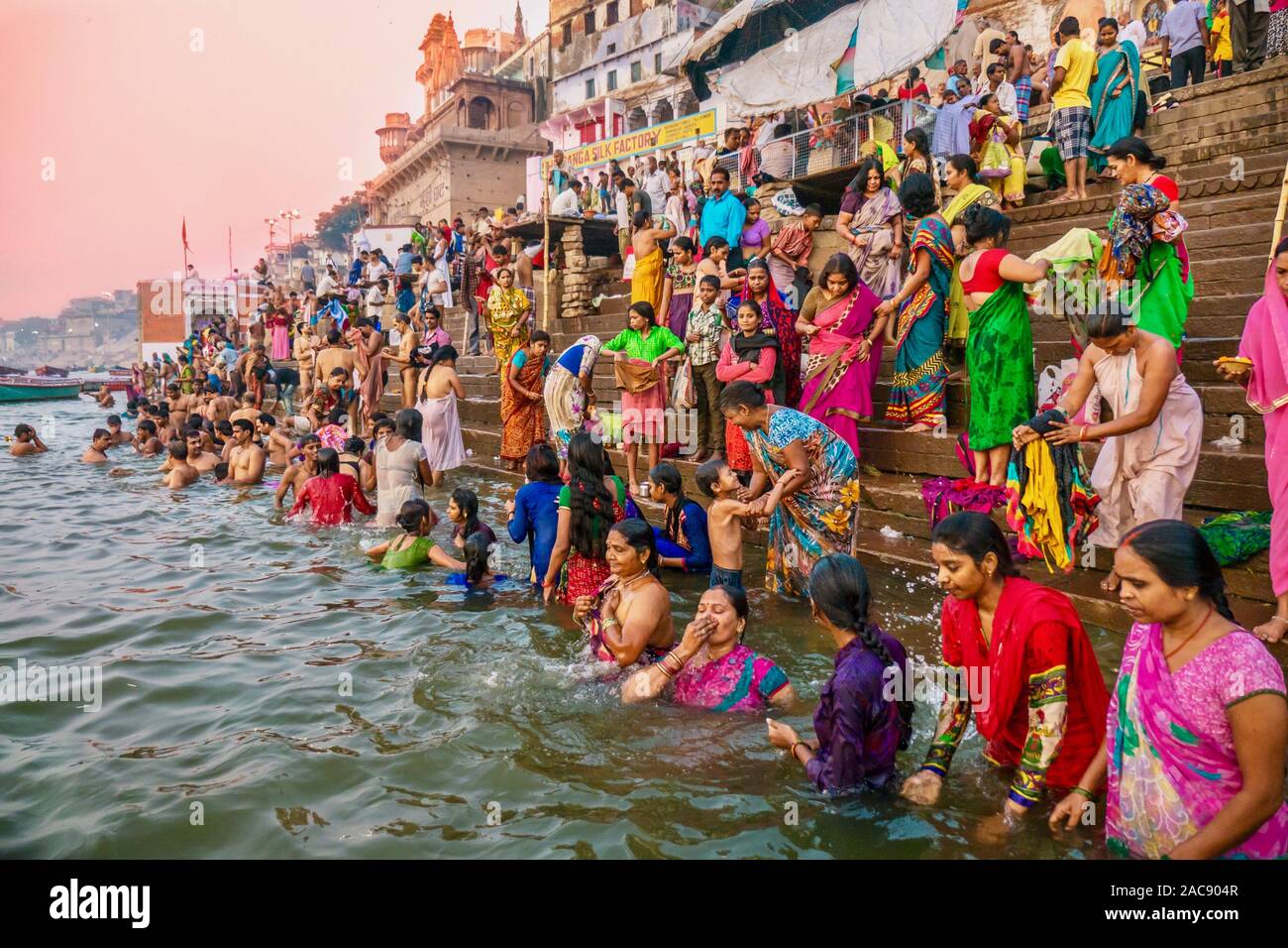 Colorful traditional clothing and Hindu religious ritual of bathing in the Ganges River from the ancient ghats of Varanasi. Stock Photo