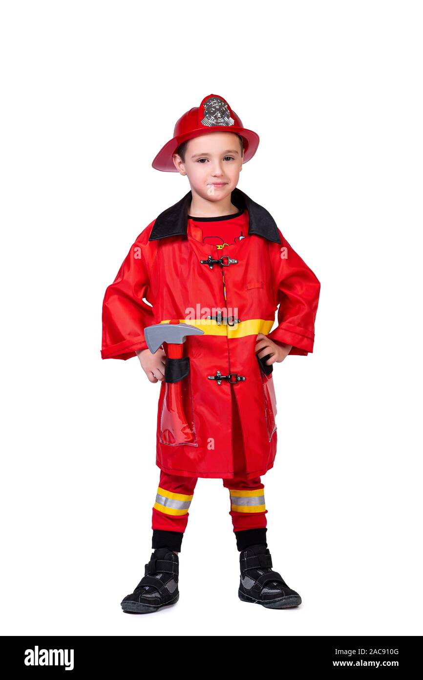 little cheerful boy in a fireman's robe: a red helmet with a coat of arms, coat, pants with stripes and an ax on a white isolated background. CONCEPT Stock Photo