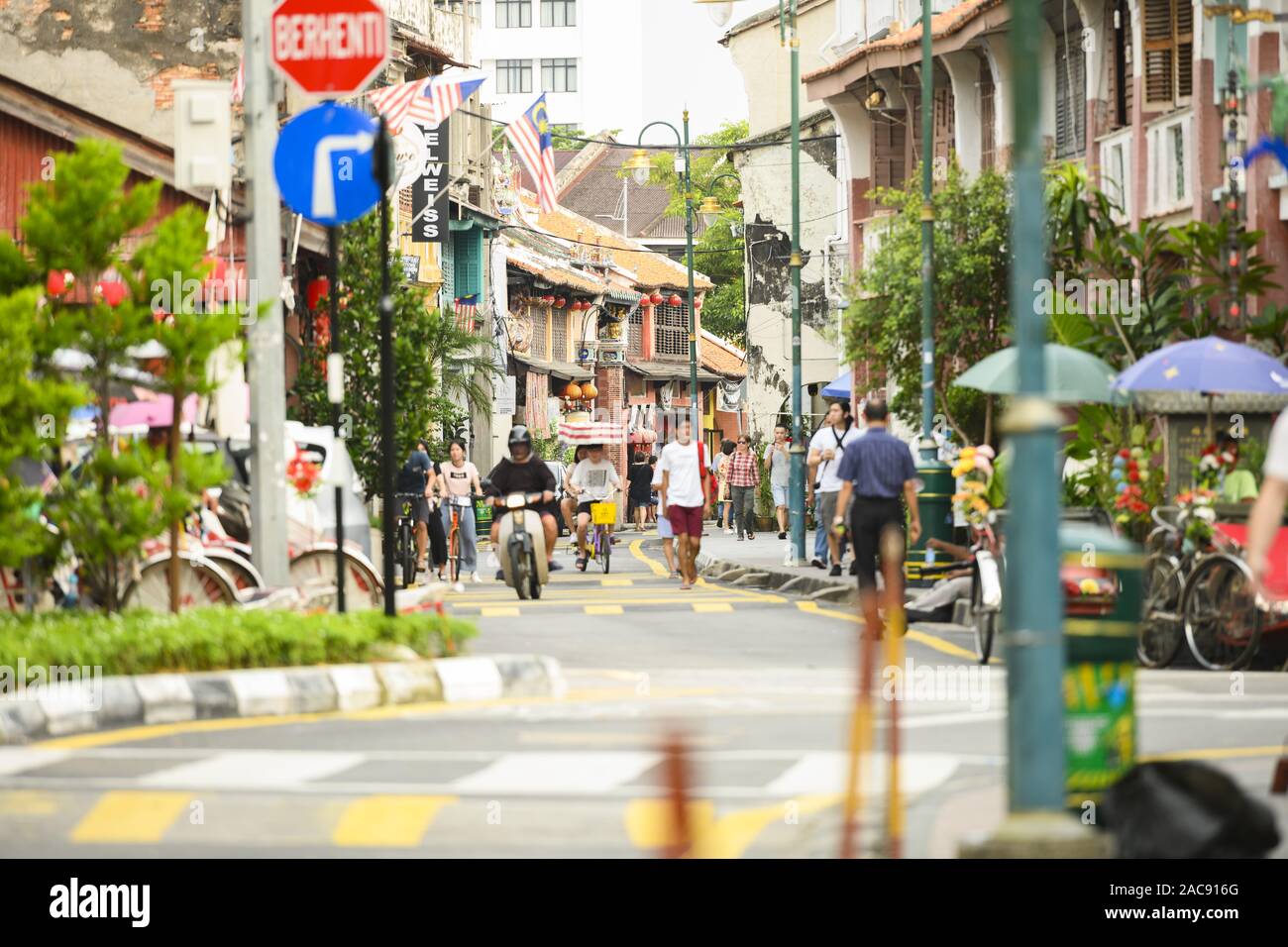 Some tourists are walking and cycling in Armenian Street in George Town. Stock Photo